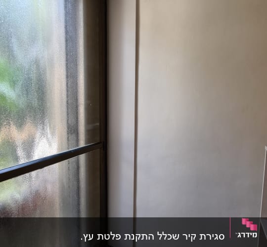 קיר עם חלון זכוכית גדול ומסגרת מתכת